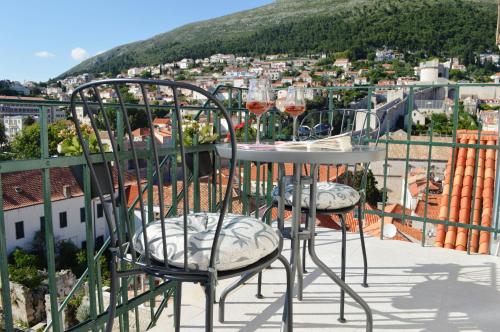 a table and chairs on a balcony with wine glasses at Dubrovnik Rupe Apartment in Dubrovnik