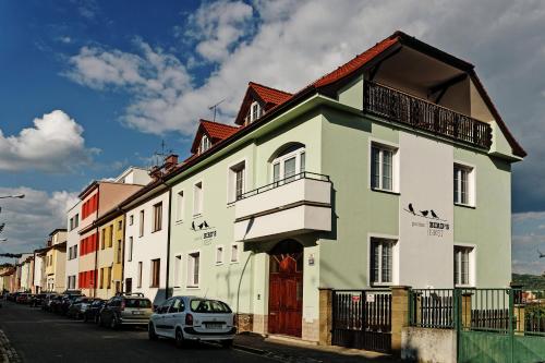 un edificio blanco y verde con coches aparcados en la calle en Penzion Bird's Nest, en Brno