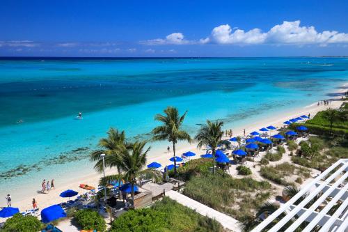 z powietrza widok na plażę z niebieskimi parasolami i ocean w obiekcie Windsong on the Reef w mieście Grace Bay