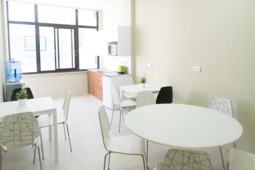 un comedor con mesas y sillas blancas en Manolia City Residences, en Nicosia