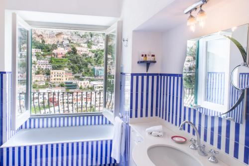 uma casa de banho azul e branca com uma banheira e uma janela em Hotel Poseidon em Positano