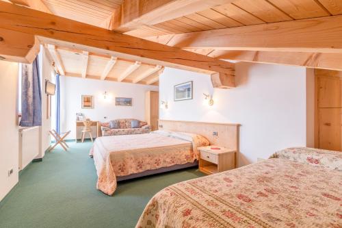 una habitación de hotel con 2 camas y una silla en Hotel Garni la Stua, en Selva di Cadore