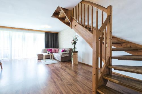 a living room with a wooden staircase and a couch at Apparthotel AlpenChalet in Neukirchen am Großvenediger