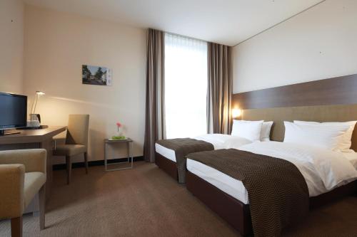 een hotelkamer met 2 bedden, een bureau en een televisie bij IntercityHotel Mannheim in Mannheim