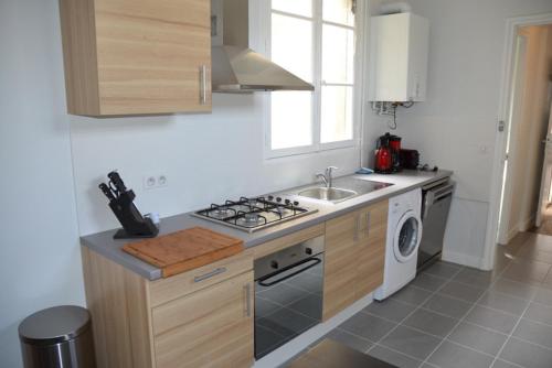 een keuken met een fornuis bovenoven naast een gootsteen bij Appartement Chaussee du Sillon in Saint-Malo