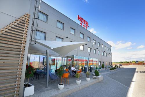 een gebouw met tafels en stoelen en een paraplu bij Hotel Porto in Radomsko