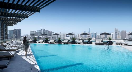 Eine Frau, die neben einem Pool auf einem Gebäude steht. in der Unterkunft Four Seasons Hotel Abu Dhabi at Al Maryah Island in Abu Dhabi