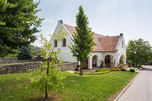 uma casa branca com uma parede de pedra em Figula Vendégház em Balatonfüred