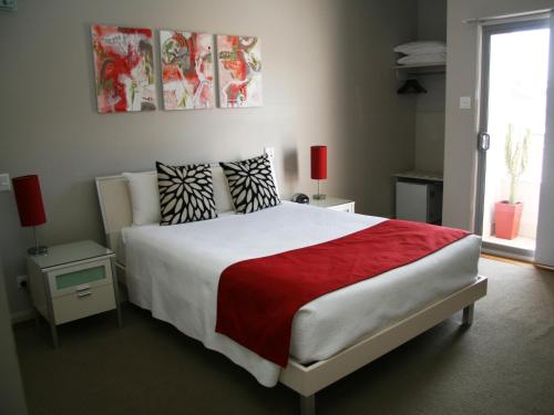 1 dormitorio con 1 cama grande con manta roja en Chaucer Palms Boutique B&B, en Newcastle