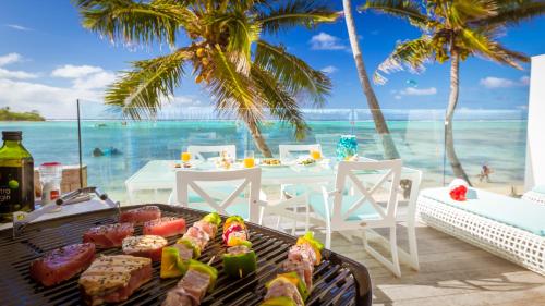 een grill met eten op een strand met de oceaan bij Crystal Blue Lagoon Villas in Rarotonga