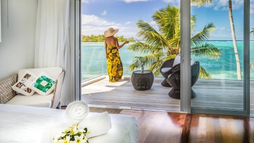 een vrouw op een balkon met uitzicht op de oceaan bij Crystal Blue Lagoon Villas in Rarotonga