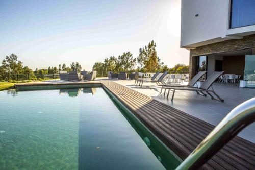 una piscina con sedie in una casa di Enigma - Nature & Water Hotel a São Teotónio