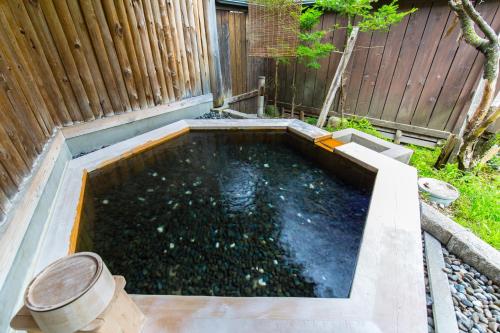 uma piscina de água num quintal com uma cerca de madeira em Kazeya em Takayama