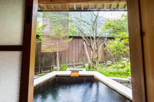 uma piscina de mergulho num jardim através de uma porta em Kazeya em Takayama