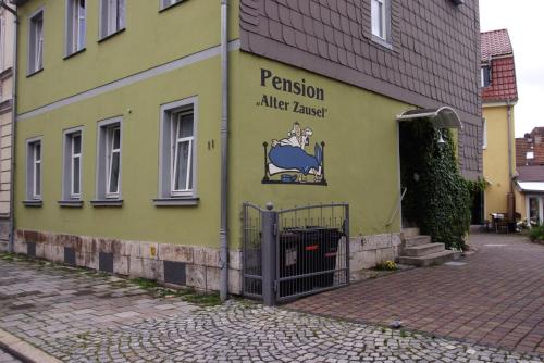 un edificio giallo con un cartello sul lato di Pension Alter Zausel a Weimar