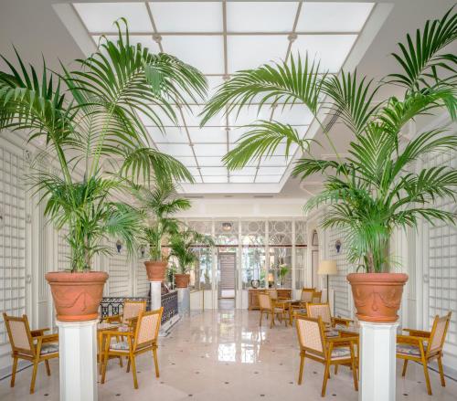 een lobby met palmbomen in grote potten bij Grand Hotel Excelsior Vittoria in Sorrento