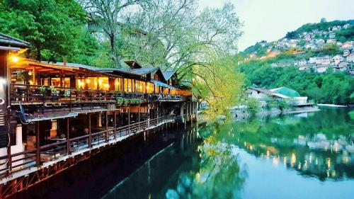 um restaurante ao lado de um rio com um edifício em Pansion River em Saraievo