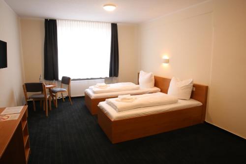 pokój hotelowy z 2 łóżkami i stołem w obiekcie City-Pension Magdeburg w mieście Magdeburg