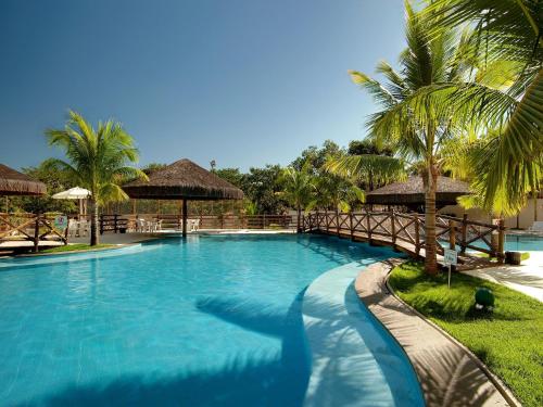 une grande piscine avec un pont et des palmiers dans l'établissement Apartamento Suites Le Jardin Caldas Novas Goiás, à Caldas Novas