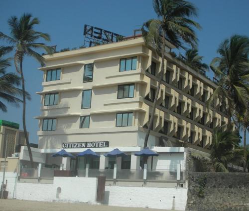 een hotel op het strand met palmbomen en parasols bij Citizen Hotel in Mumbai