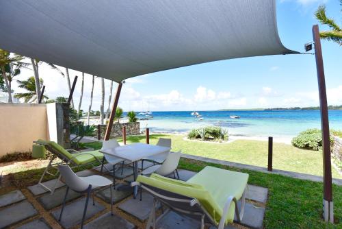 um pátio com uma mesa e cadeiras e a praia em Turquoise Bay Beach Apartments Trou d'Eau Douce em Trou dʼ Eau Douce