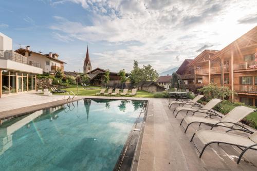 a swimming pool with chairs and a church at Apartment Lodge Gasserhof in Bressanone