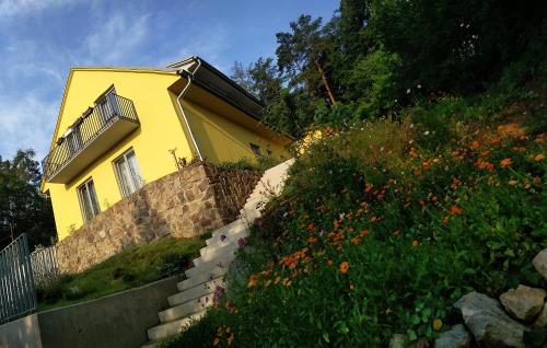 una casa gialla sul fianco di una collina con fiori di Mezi Stromy a Brno