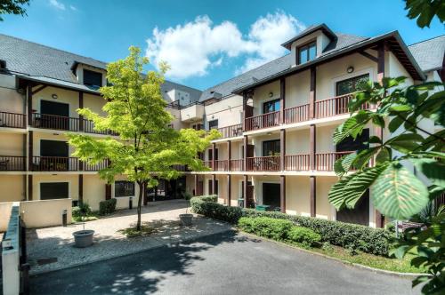 - une vue sur l'extérieur d'un bâtiment avec une cour dans l'établissement Zenitude Hôtel-Résidences l'Acacia Lourdes, à Lourdes