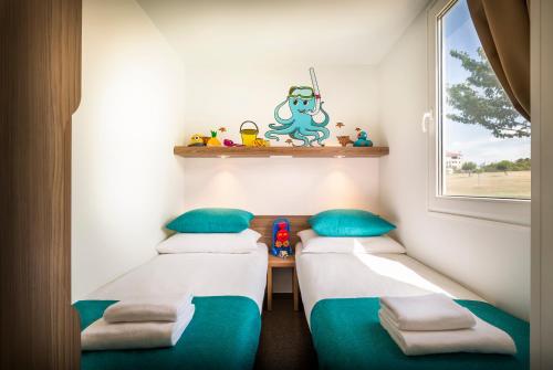 2 Betten in einem kleinen Zimmer mit Fenster in der Unterkunft Aminess Maravea Camping Resort Holiday Homes in Novigrad Istria