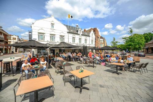 eine Gruppe von Personen, die vor einem Gebäude an Tischen sitzen in der Unterkunft Brasserie-Hotel Antje van de Statie in Weert