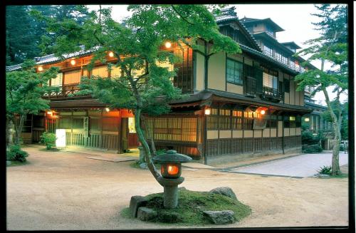 un piccolo albero di fronte a un edificio con una casa di Iwaso a Miyajima