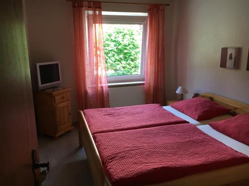 - une chambre avec un lit doté de draps rouges et une fenêtre dans l'établissement Pension Villa Strandläufer, à Norddeich