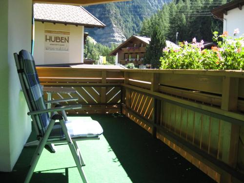 a chair on a balcony with a fence and flowers at Haus Kristall in Längenfeld