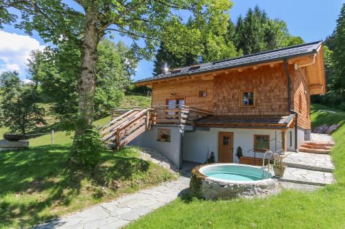 uma casa de madeira com uma piscina em frente em Chalet Die Mühle em Saalfelden am Steinernen Meer