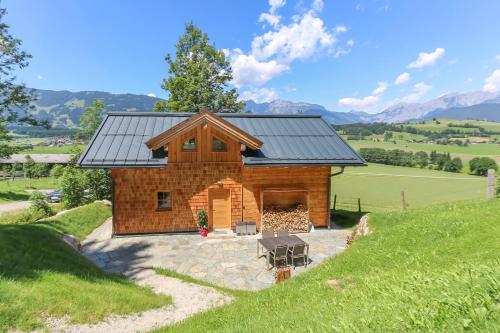 uma cabana de madeira com um telhado solar numa colina em Chalet Die Mühle em Saalfelden am Steinernen Meer