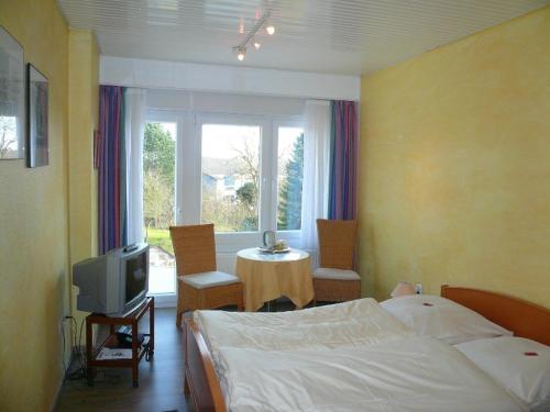 Schlafzimmer mit einem Bett, einem TV und einem Fenster in der Unterkunft Hotel-Restaurant Nord-Stuv in Cuxhaven