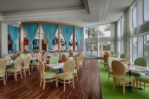 un comedor con mesas, sillas y ventanas en Moody Gardens Hotel Spa and Convention Center, en Galveston