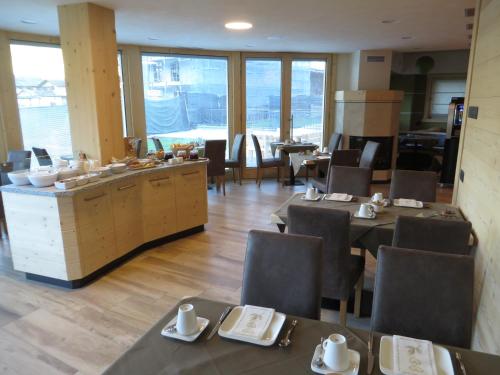 a dining room with tables and chairs and windows at B&B Ecohotel Chalet des Alpes in Livigno