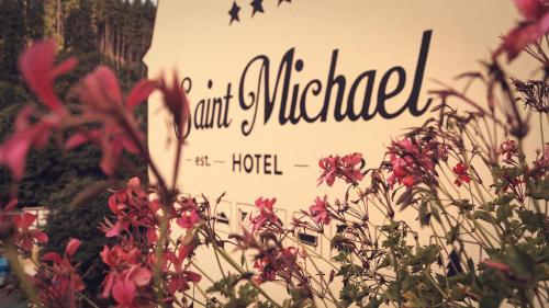 un panneau pour un hôtel avec des fleurs devant lui dans l'établissement Hotel St.Michael, à Karlovy Vary