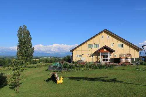 a barn with a cow laying in the grass at Pension Ken&Mary in Biei