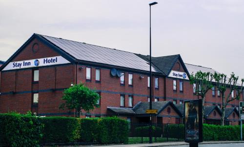 un grand bâtiment en brique rouge avec un panneau. dans l'établissement Stay Inn Manchester, à Manchester