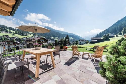 een patio met een tafel en stoelen en een parasol bij Chalet Sophia in Ortisei