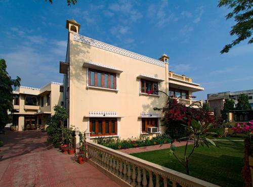 un bâtiment blanc avec une clôture à côté d'une cour dans l'établissement Dera Rawatsar - Heritage Hotel, à Jaipur