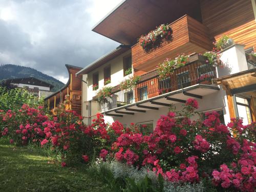 ein Gebäude mit rosa Blumen davor in der Unterkunft Garni Enrosadira in Vigo di Fassa