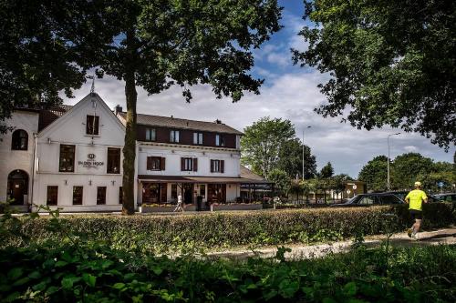 un homme marchant devant un bâtiment blanc dans l'établissement Hotel Restaurant in den Hoof, à Maastricht