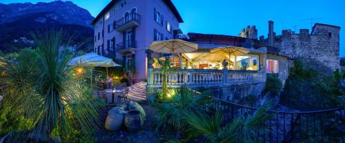 un bâtiment avec des parasols en face d'un restaurant dans l'établissement Villa Miravalle, à Riva del Garda