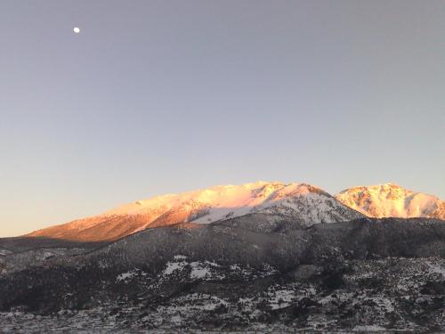 een berg bedekt met sneeuw met de maan in de lucht bij Pasithea Mountain Chalet in Feneos