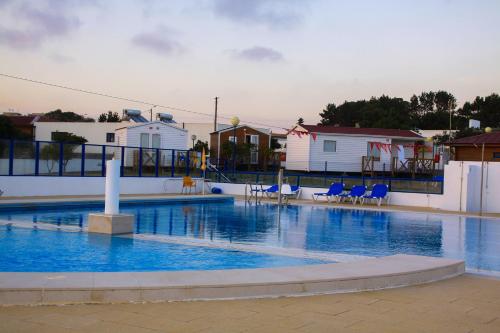 una gran piscina con sillas azules y edificios en Parque de Campismo Orbitur Canidelo, en Vila Nova de Gaia