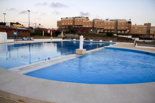 una gran piscina azul con edificios en el fondo en Parque de Campismo Orbitur Canidelo, en Vila Nova de Gaia