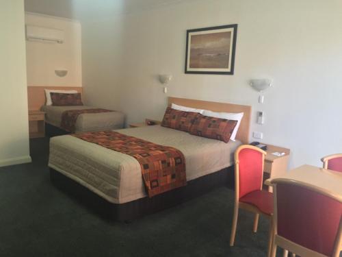 a hotel room with two beds and a table and chairs at Abel Tasman Motor Inn in Dubbo